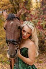 Fototapeta premium A woman in dress stands next to a horse. Horseback riding in the autumn forest