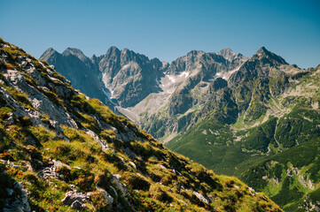 High Tatras rising like giants from the gentle slopes of the Belianske Tatras, set against a backdrop of pure blue skies
