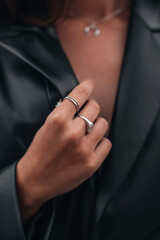 Close up fashion details of a black leather jacket and silver ring accessories. Fancy outfit,...