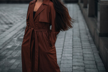 Woman walking alone in the city. Fancy details of autumn long brown leather trench coat. Street...