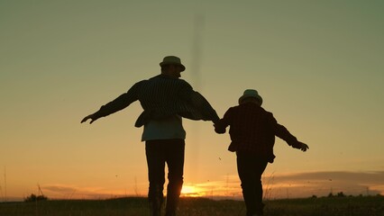 Father, child son run together holding hands, sunset. Kid dad travel in park, happy family. Silhouette. Dad plays with his kid outdoors, walk in park. Childhood dream, fatherly. Child, Dad, fly Sky