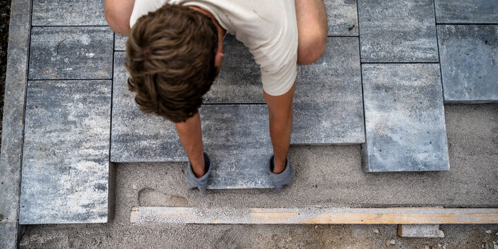 Man in a DIY project precisely laying grey concrete cement tiles