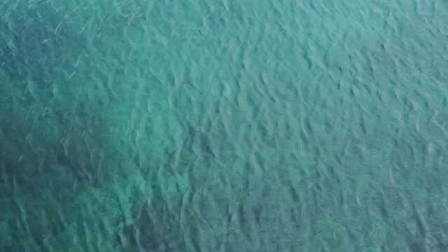Continuously changing turquoise sea or ocean surface for a background. Beautiful and fresh blue wavy water, calm and meditative nature concept. Refreshing, abstract and minimalistic 4K slow motion.