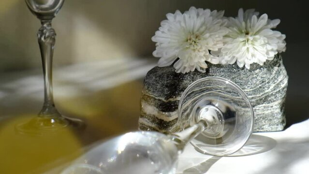 Moving wine glass and caustic refraction light, flowers and stone podium