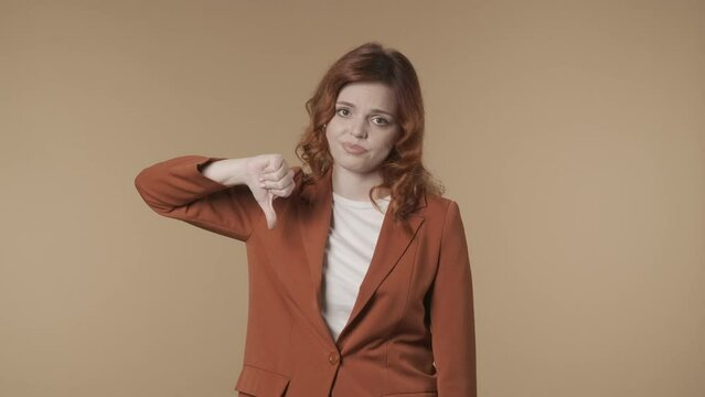 Medium isolated video of a young woman looking at the camera and giving thumbs-down to show her disagreement, complaint about something. HDR BT2020 HLG Material.
