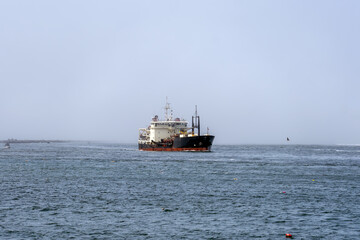 Large Army Corps of Engineers ship sailing into Winchester Bay Oregon on a foggy afternoon.