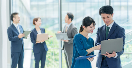 オフィスの廊下で立ち話をするビジネスパーソン