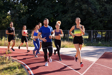 Group of people running at stadium on sunny day