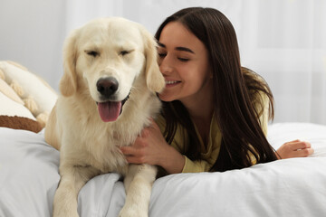 Happy woman with cute Labrador Retriever dog on bed at home. Adorable pet