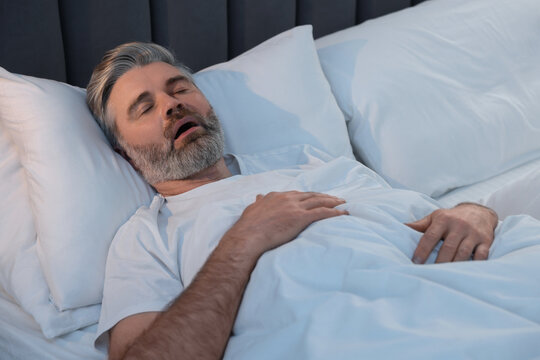 Man snoring while sleeping in bed at home