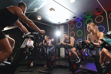 Group of people training on exercise bikes in fitness club