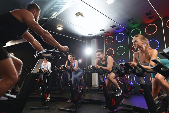 Group of people training on exercise bikes in fitness club