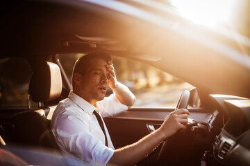 Young caucasian businessman is tired while driving the car to work