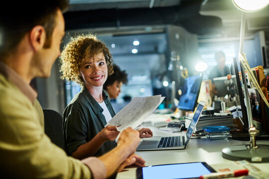 Young caucasian woman going over paperwork with a coworker in a startup company office