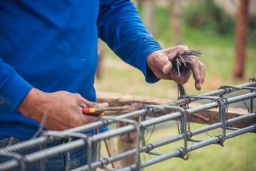 Men hands using pincer pliers iron wire reinforcement of concrete work. Construction Worker hands bending cutting steel wire fences bar. Outdoor Worker using wire bending pliers, construction work. - obrazy, fototapety, plakaty