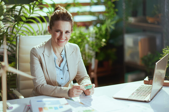 smiling business woman in light business suit in green office