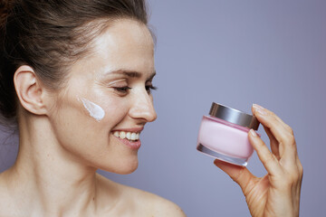 happy modern 40 years old woman with cosmetic cream jar
