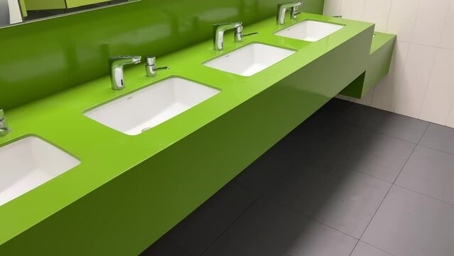 Rows of modern square washbasins in a public restroom