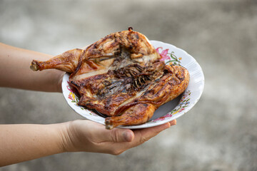 Roast chicken on a plate in the hands of a child.