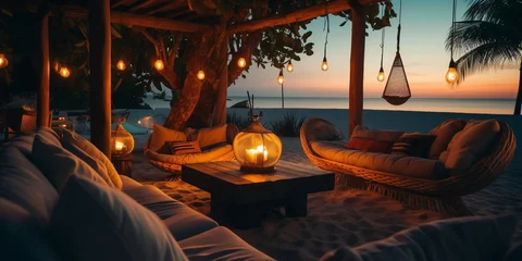 Fototapeten cozy Luxury resort, evening beach, candles blurred light on table ,sofa, hammock on front sunset sea ,tropical plan and palm © Aleksandr