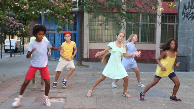 Young boys and girls dancing outdoors. They're performing street dance moves and having fun.
