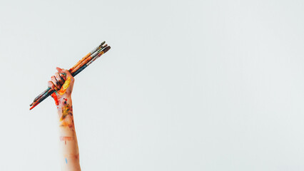 Painting brush. Art accessories. Unrecognizable woman painter hand holding messy acrylic paint colorful kit of paintbrushes isolated on white empty space background.