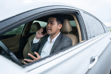 Asia man having phone conversation angry in car and raining