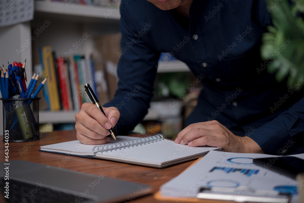 Poster man hands with pen writing on notebook in the office.learning, education and work.writes goals, plan
