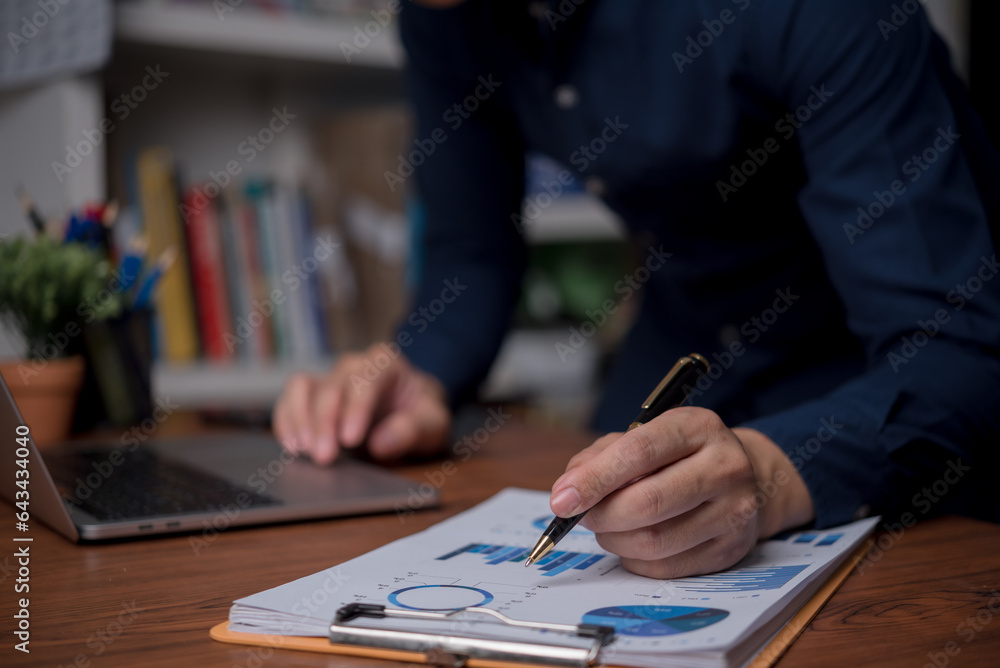 Poster businessman is using a laptop and pointing to a marketing graph working on analyzing financial repor