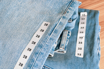 Couple's matching blue jeans with size labels. Close up shot, selective focus.