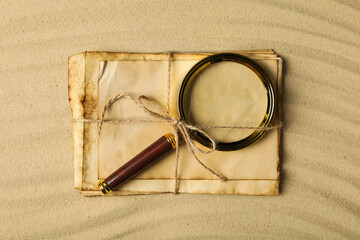 Columbus Day. A magnifying glass with a stack of letters on the sand