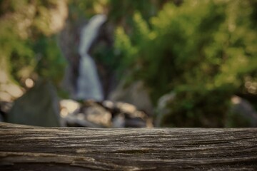 Wooden surface at waterfall in mountains 