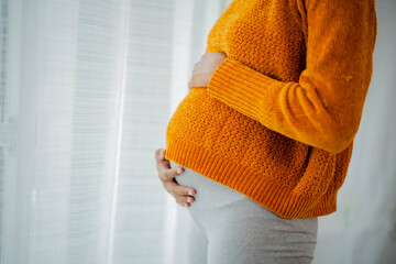Crop of African American pregnancy woman in yellow sweater and gray legging standing beside glasses...