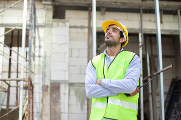 Construction engineer. happy man engineer wear uniform standing at construction site. Workers supervise construction inspection of building.