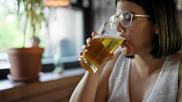 Young beautiful hispanic woman drinking beer at the restaurant