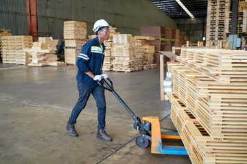 African American worker examining stock of timber while working at wood warehouse.