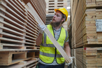 Warehouse worker working at lumber yard in Large Warehouse. Worker are  Inventory check at Storage shelves in lumberyard.