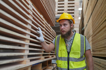 Warehouse worker working at lumber yard in Large Warehouse. Worker are  Inventory check at Storage shelves in lumberyard.
