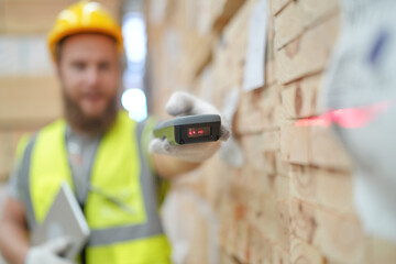 Warehouse worker working at lumber yard in Large Warehouse. Worker are  Inventory check at Storage shelves in lumberyard.