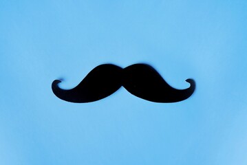 Top view image of fake mustache on blue background with copy space. Masculine, movember and hipster...