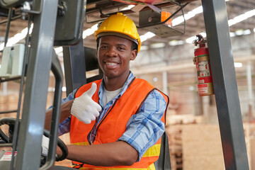 African American worker examining stock of timber while working at wood warehouse.