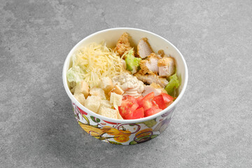 Salad with chicken meat, cheese, tomatoes and crouton in cardboard bowl