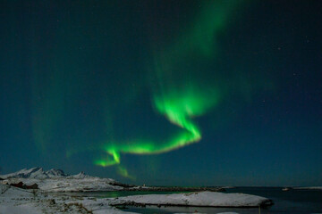 Wide angle shot of the aurora borealis, the northern lights, over the Norwegian islands near Mjelle on a winter evening.