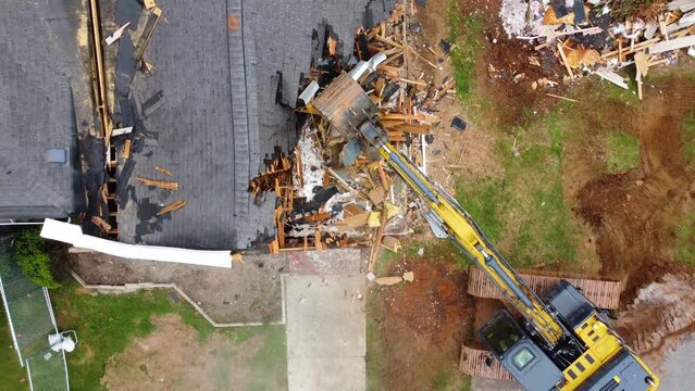 A top down drone shot of an excavtor starting to tear down a building.