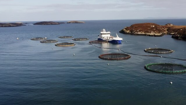 Ascending drone shot of a fish farm and a well-boat near the Isle of Uist.