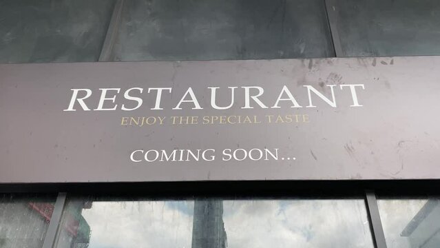Restaurant enjoy the special taste coming soon sign store front with reflection of buildings in window glass mirror daytime, Bangkok, Thailand. Food business concept 