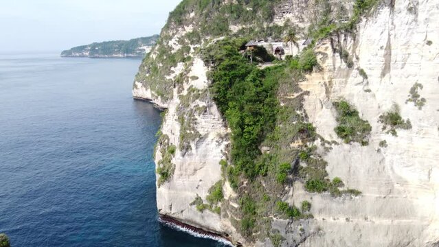 Rumah Pohon Tree House on edge of steep limestone cape cliff, craggy coast of Nusa Penida Island, Indonesia