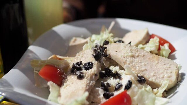 putting olive oil on chicken vegetable salad 