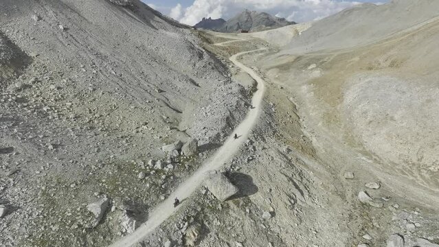 Motorcyclist on gravel road shortly in front of the summit at Colle Sommeiller, also Col du Sommeiller, Alps in the French-Italian border area, aerial view, drone shot, Bardonecchia, Piemonte, Italy