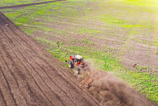 Aerial view of agricultural tractor doing stubble field fall tillage on farmland, top view from drone
